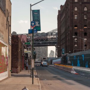 The old Domino sugar factory on the right and a glimpse of the Williamsburg Bridge A street in Williamsburg facing the bridge. The Domino sugar factory