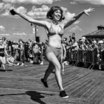A woman leaping into the air at the Mermaid Parade on the boardwalk in Coney Island